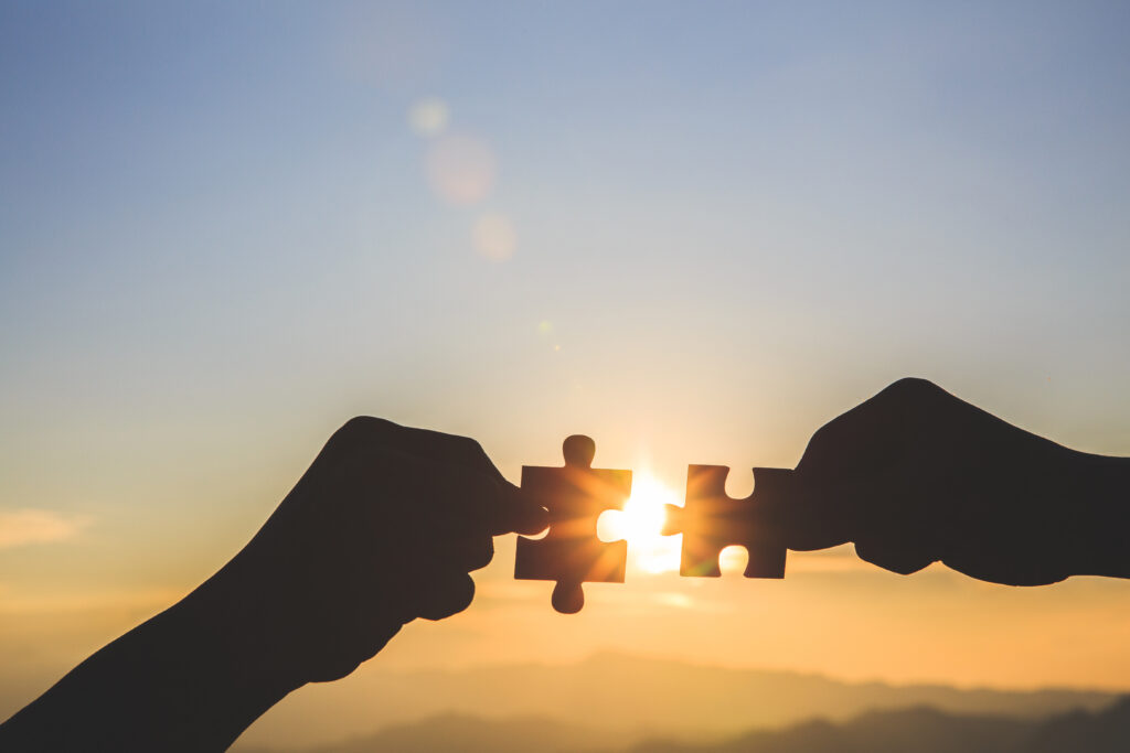 Puzzle-Stücke vor dem Sonnenuntergang als Symbol für die Idee hinter Sentalis: erfolgreiche Zusammenarbeit und harmonische Beratung.